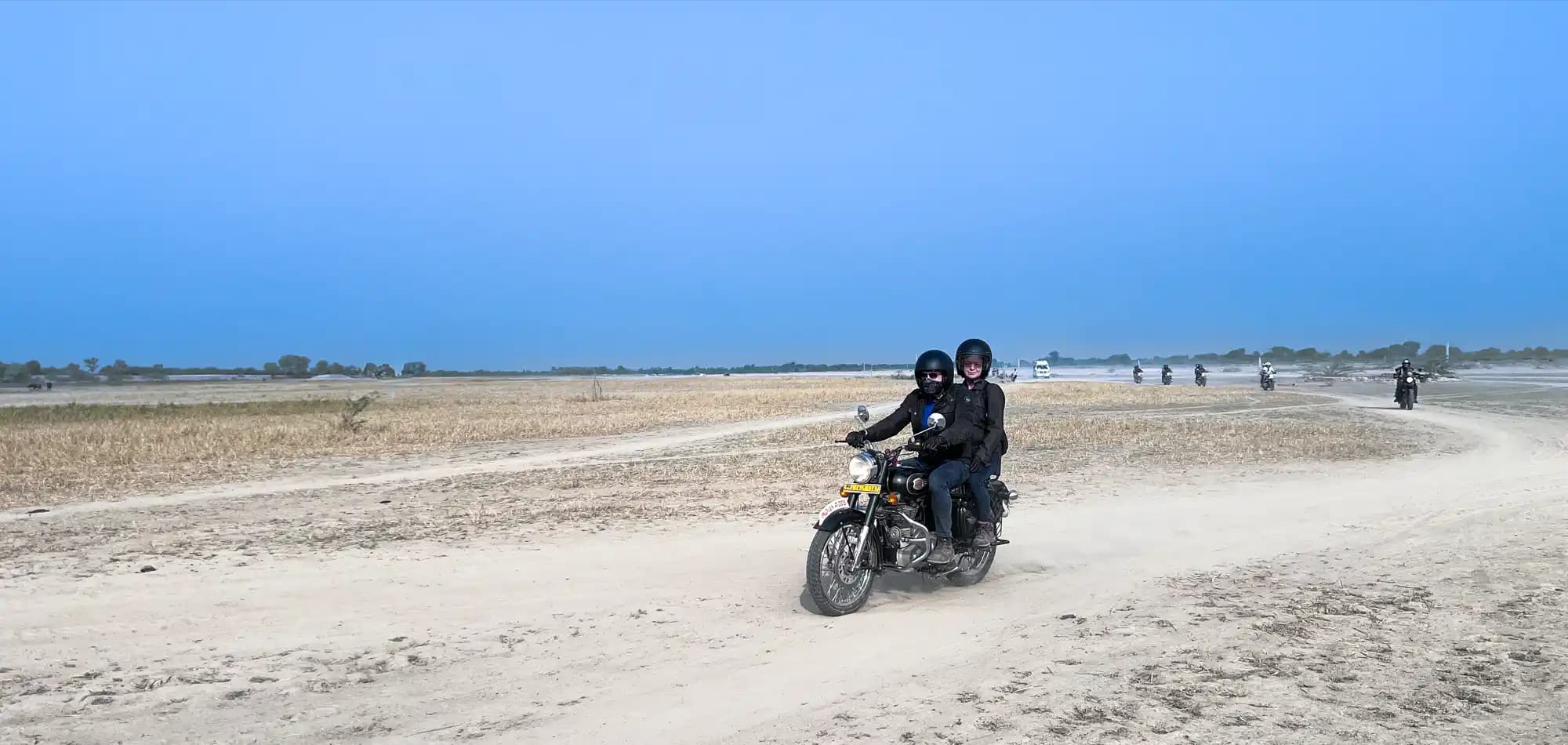 Motorradfahrer auf einer Royal Enfield auf einer unbefestigten Straße in Rajasthan Motorradfahrer auf einer Royal Enfield auf einer unbefestigten Straße in Rajasthan