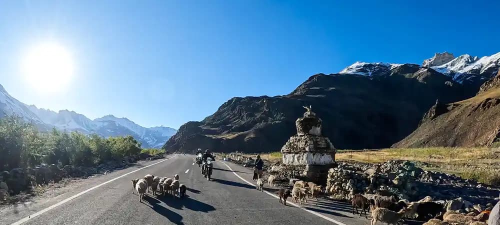 Motorrad auf einer Bergstraße im Himalaya mit schneebedeckten Bergen in Ladakh Motorrad auf einer Bergstraße im Himalaya mit schneebedeckten Bergen in Ladakh